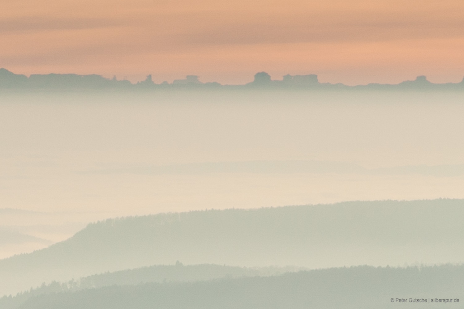 A detail from a panorama showing the slightly distorted mountain range with the Stockhorn and the range behind. The distant mountain ranges are slightly brighter due to the haze of the distance. Therefore, one can just about recognize that these mountains are further away than the main ridge in the center of the image. The distant silhouette, which we identify as the Mont Blanc massif, is so distorted here that the upper part of the silhouette seems to detach from the rest of the outline and thus appears like a reflection.