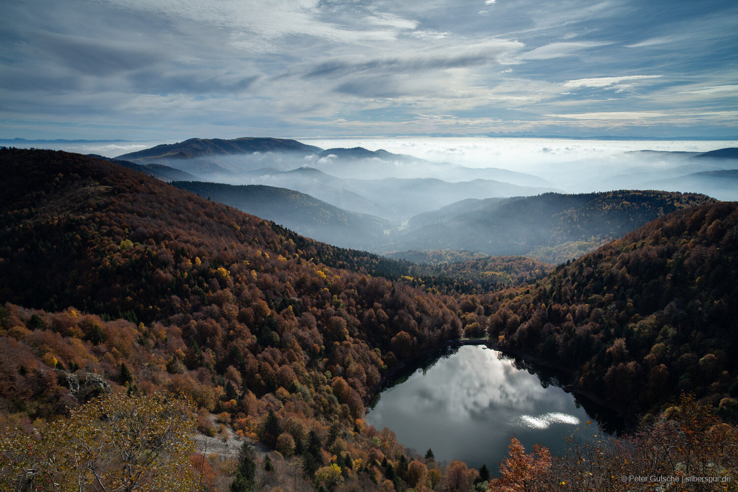 A lake seen from above with the sun light brighly reflected by the lake surface.